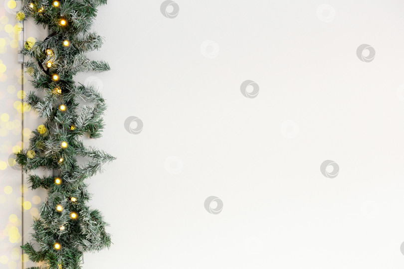 Скачать рождественский декоративный фон. Поздравительная новогодняя открытка. Еловая гирлянда на белом фоне. Место для текста фотосток Ozero