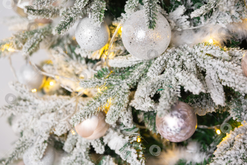 Скачать Новогодний игрушечный шар висит на ветке ели. Новогодняя елка украшена гирляндой. фотосток Ozero