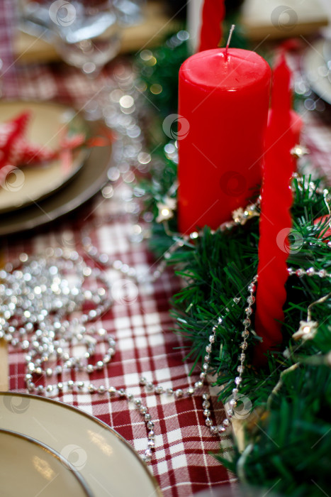Скачать Красные свечи в зеленой мишуре на красной клетчатой скатерти фотосток Ozero