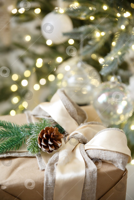 Скачать Подарок в коробке на фоне горящей новогодней гирлянды и новогодней елки фотосток Ozero