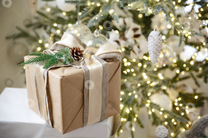 Скачать Подарок в коробке на фоне горящей новогодней гирлянды и новогодней елки фотосток Ozero