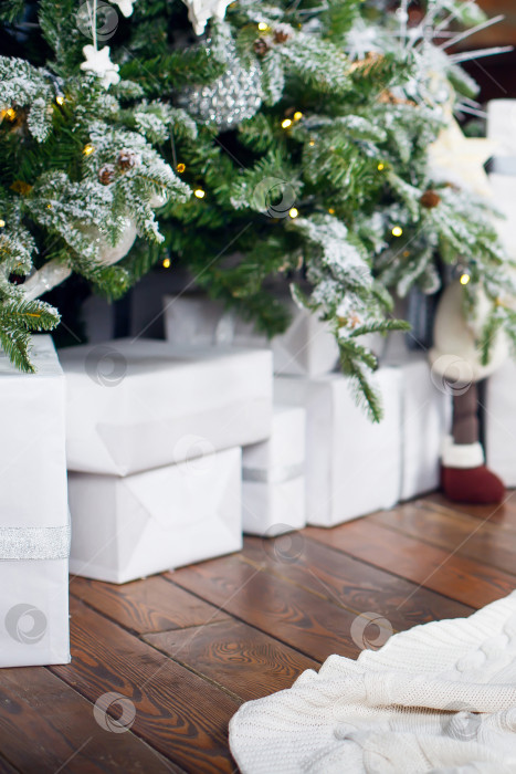 Скачать Подарки в коробках в упаковке лежат под рождественской елкой на деревянном полу. фотосток Ozero
