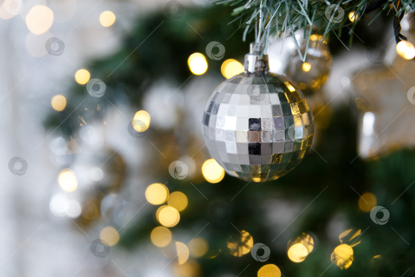 Скачать Рождественский игрушечный шар на ветке, на фоне боке-огней гирлянд фотосток Ozero