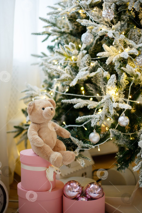 Скачать Игрушечный плюшевый мишка на рождественской елке, украшенной желтыми гирляндами фотосток Ozero