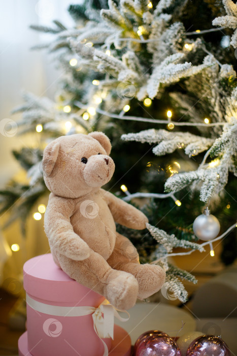 Скачать Игрушечный плюшевый мишка на рождественской елке, украшенной желтыми гирляндами фотосток Ozero