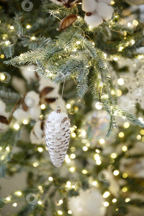 Скачать Новогодняя игрушка еловая шишка, висящая на ветке ели фотосток Ozero