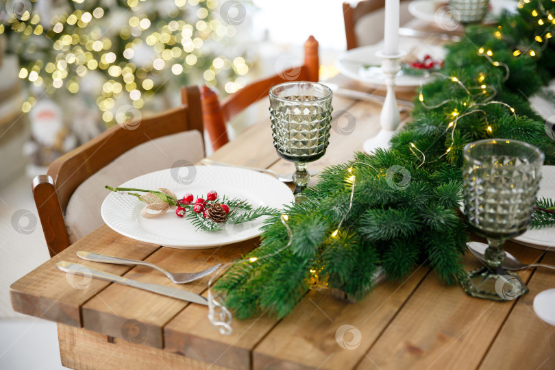 Скачать Сервировка стола с использованием посуды. Праздничное оформление еловыми ветками и гирляндами фотосток Ozero