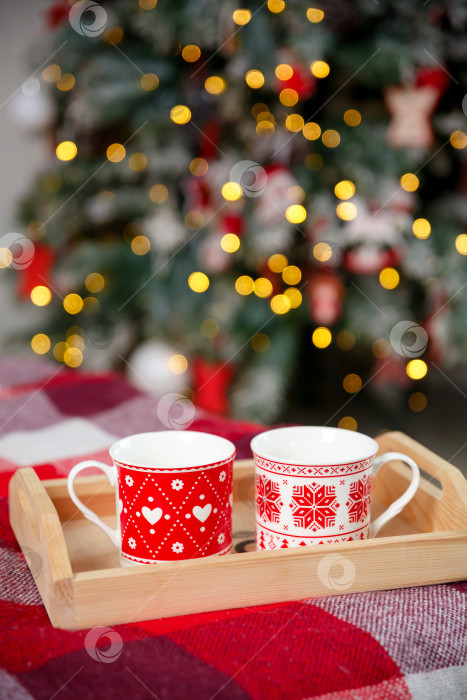 Скачать Кружки на деревянном подносе возле рождественской елки. Концепция уютного домашнего вечера фотосток Ozero