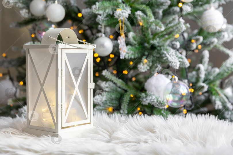 Скачать белый фонарь на меховой подкладке, на фоне горящих елочных гирлянд. Новогодняя или рождественская открытка фотосток Ozero