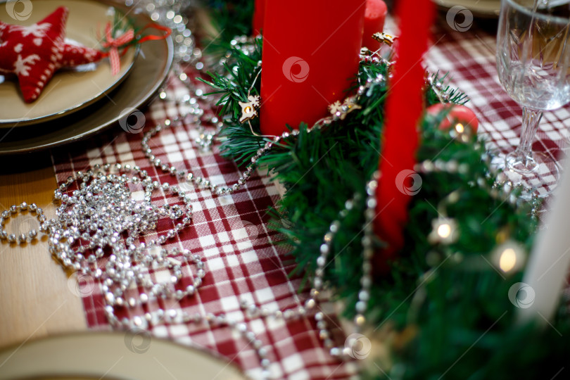 Скачать Красные свечи в зеленой мишуре на красной клетчатой скатерти фотосток Ozero