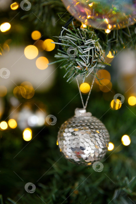 Скачать Новогоднее украшение - шар из пайеток на фоне веток и огоньков гирлянд фотосток Ozero