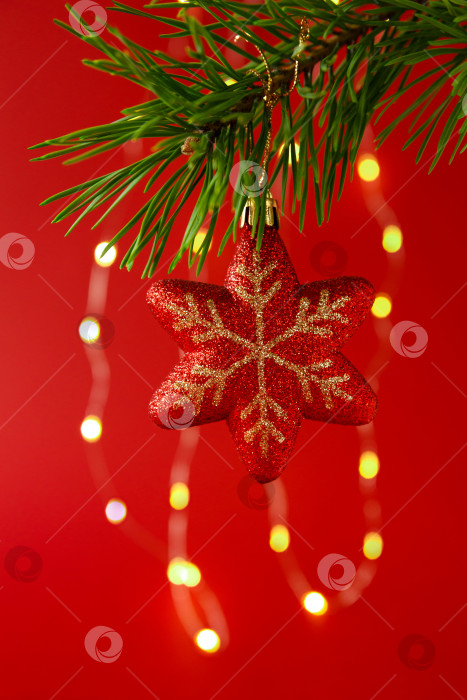 Скачать Новогодняя игрушка, висящая на еловой ветке, на фоне гирлянды фотосток Ozero