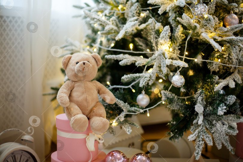 Скачать Игрушечный плюшевый мишка на рождественской елке, украшенной желтыми гирляндами фотосток Ozero