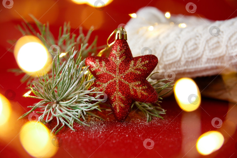 Скачать Рождественская игрушка и еловая ветка на фоне вязаного свитера и гирлянды фотосток Ozero