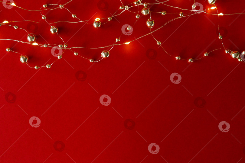 Скачать Рождественский фон. Бусы и гирлянда на красном фоне фотосток Ozero