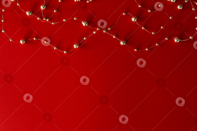 Скачать Рождественский фон. Бусы и гирлянда на красном фоне фотосток Ozero