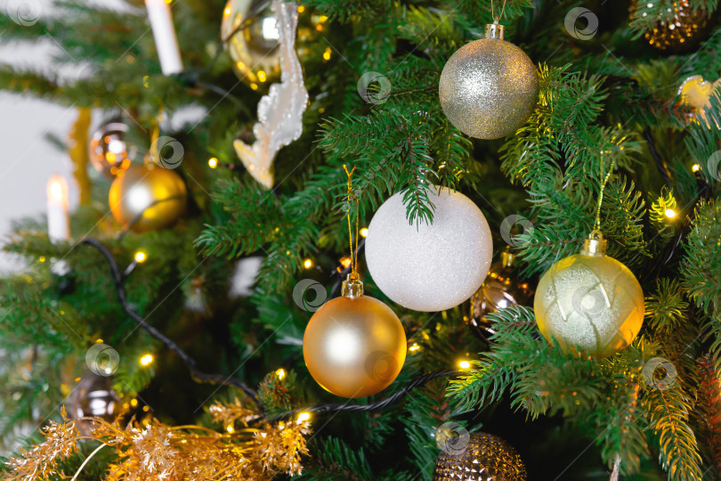 Скачать Новогодний игрушечный шар висит на ветке ели. Новогодняя елка украшена гирляндой. фотосток Ozero