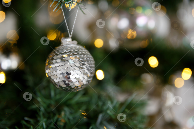 Скачать Новогоднее украшение - шар из пайеток на фоне веток и огоньков гирлянд фотосток Ozero