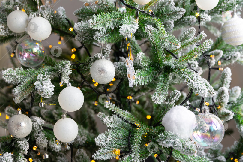 Скачать Новогодний игрушечный шар, висящий на ветке ели. Новогодняя елка украшена гирляндой фотосток Ozero
