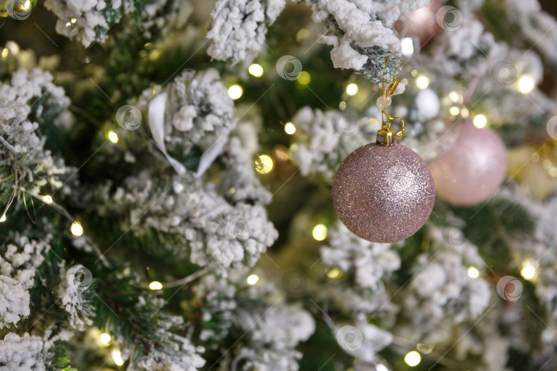 Скачать Белая рождественская игрушка, висящая на зеленой заснеженной еловой ветке фотосток Ozero