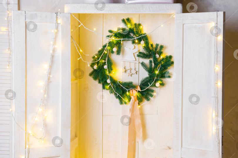 Скачать Рождественский венок и гирлянда в белом деревянном шкафу или гардеробе. Новогодний или рождественский фон фотосток Ozero