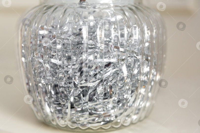 Скачать Серебряная мишура или блестящие ленты в прозрачной стеклянной вазе. Новогодний или рождественский фон фотосток Ozero