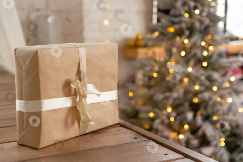 Скачать подарочная коробка на деревянной полке, на фоне горящей гирлянды из рождественской ели. Новогодний или рождественский фон. фотосток Ozero
