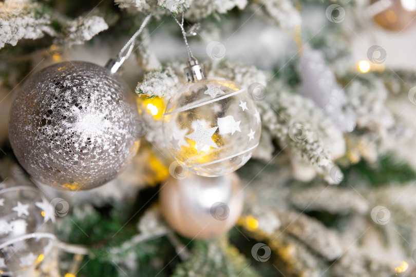 Скачать Новогодний игрушечный шар, висящий на ветке ели. Новогодняя елка украшена гирляндой фотосток Ozero