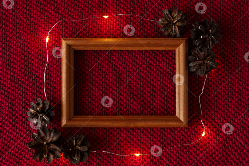 Скачать Рождественский фон. Шишки, рамка и гирлянда на трикотажной основе свитера. фотосток Ozero