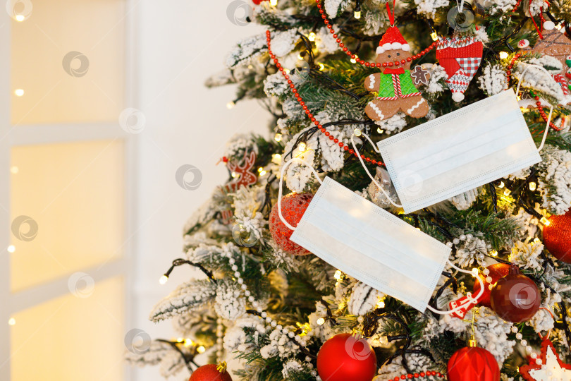 Скачать медицинская маска для лица, висящая на украшенной рождественской елке фотосток Ozero