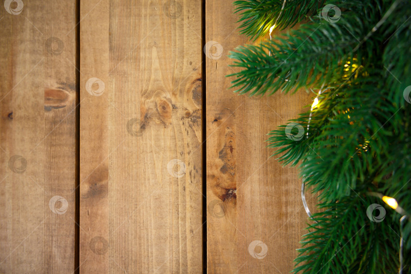 Скачать Зеленые еловые ветки с гирляндой на грубых деревянных досках. фотосток Ozero
