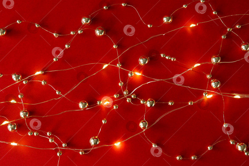 Скачать Рождественский фон. Бусы и гирлянда на красном фоне фотосток Ozero