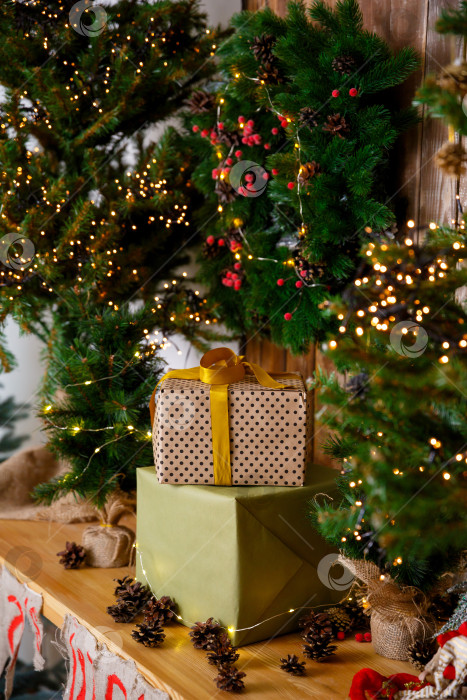 Скачать Подарки в коробках в упаковке стоят возле новогодней елки на деревянном столе фотосток Ozero