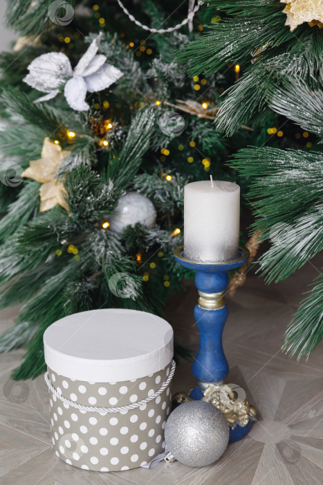 Скачать Синий подсвечник с белой свечой. Подарочная коробка под рождественской елкой. Еловые ветки на снегу. фотосток Ozero