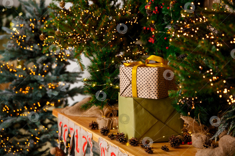 Скачать Подарки в коробках в упаковке стоят возле новогодней елки на деревянном столе фотосток Ozero