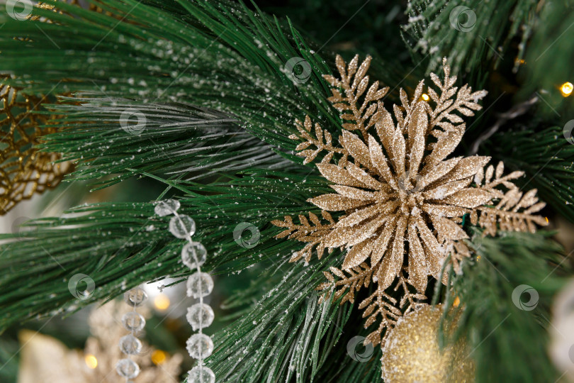 Скачать Рождественская открытка. Елочная игрушка на еловой ветке. Рождественское украшение в форме цветка. Ветка покрыта снежинками фотосток Ozero