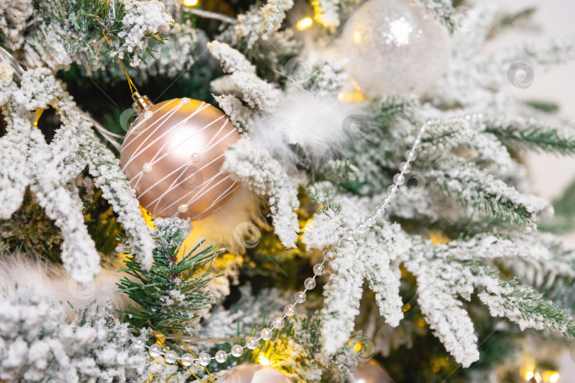 Скачать Новогодний игрушечный шар, висящий на ветке ели. Новогодняя елка украшена гирляндой фотосток Ozero