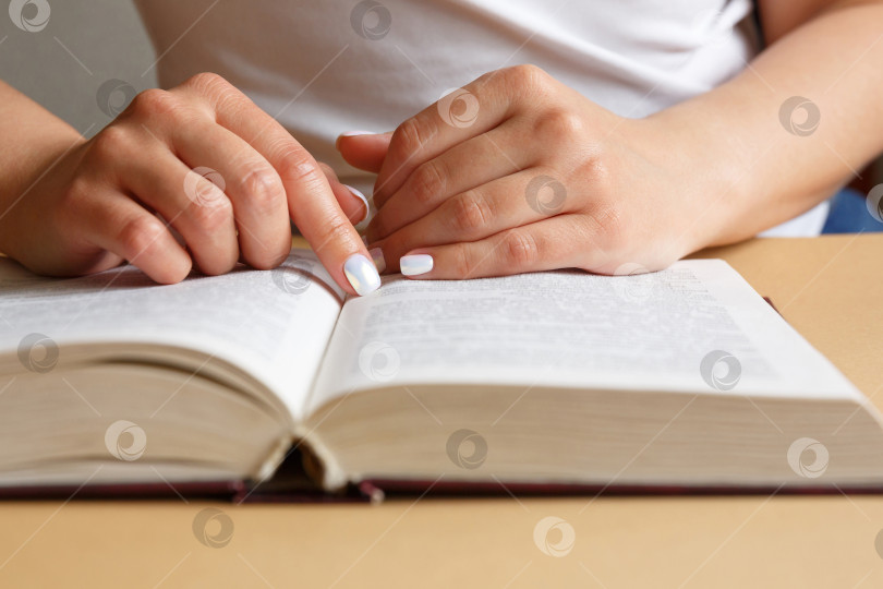 Скачать Женщина читает книгу. В руках она держит книгу. Красивый маникюр фотосток Ozero