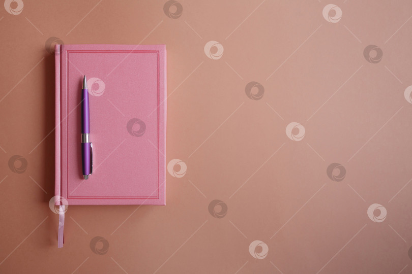 Скачать Ручка на розовом блокноте или дневнике, на бумажном фоне фотосток Ozero