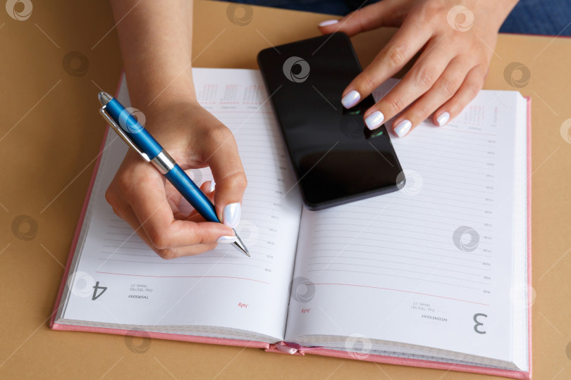 Скачать Мужчина, пишущий в дневнике и держащий в руке телефон фотосток Ozero