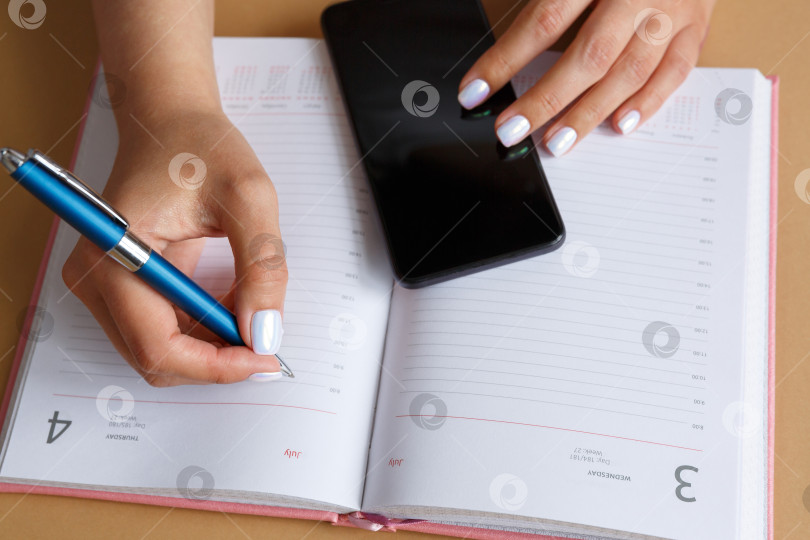 Скачать Мужчина пишет в дневнике и держит в руке телефон фотосток Ozero