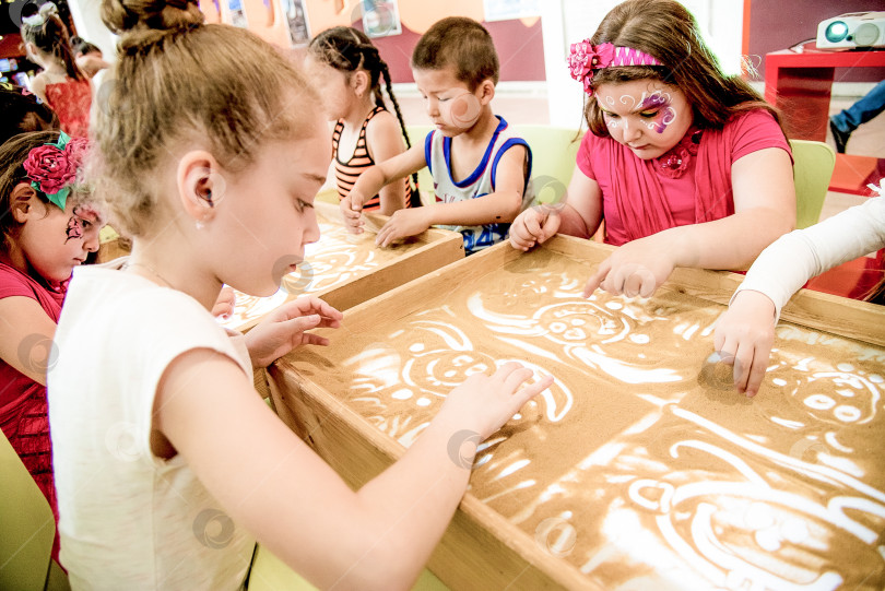 Скачать Красноярск, Россия, 28 мая 2017 года, Ребенок играет желтым песком на столе с подсветкой фотосток Ozero