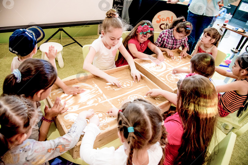 Скачать Красноярск, Россия, 28 мая 2017 года, Ребенок играет желтым песком на столе с подсветкой фотосток Ozero