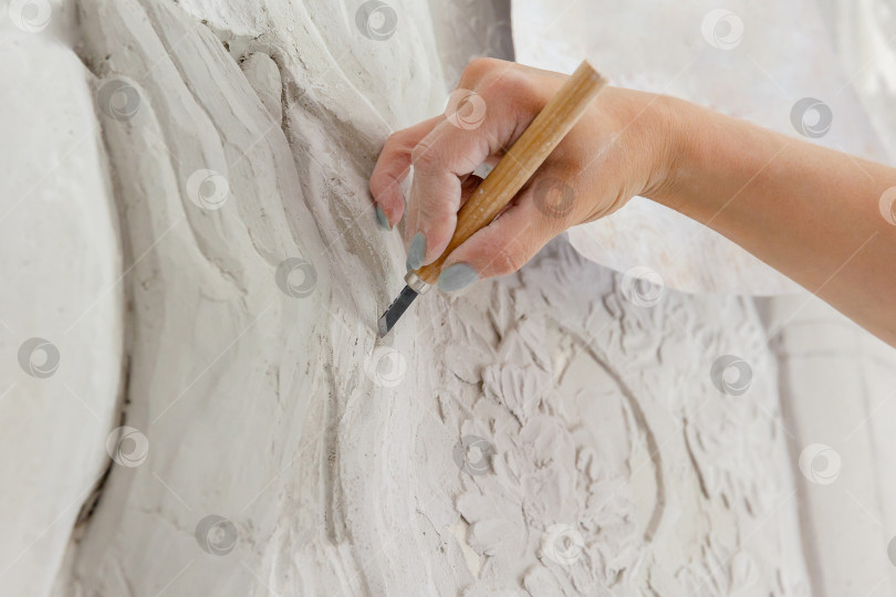 Скачать Рабочий процесс: женская рука резцом вырезает барельефный узор фотосток Ozero