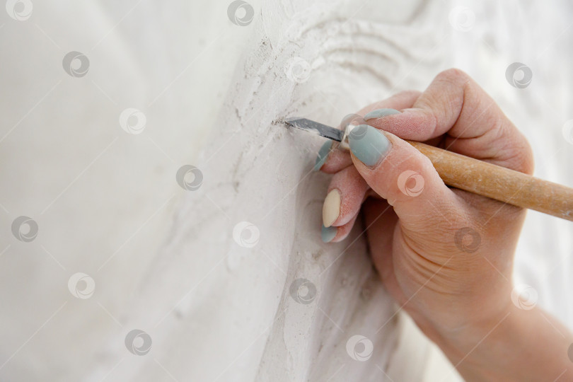 Скачать Рабочий процесс: женская рука резцом вырезает барельефный узор фотосток Ozero