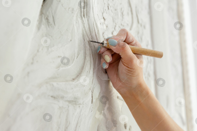 Скачать Рабочий процесс: женская рука резцом вырезает барельефный узор фотосток Ozero