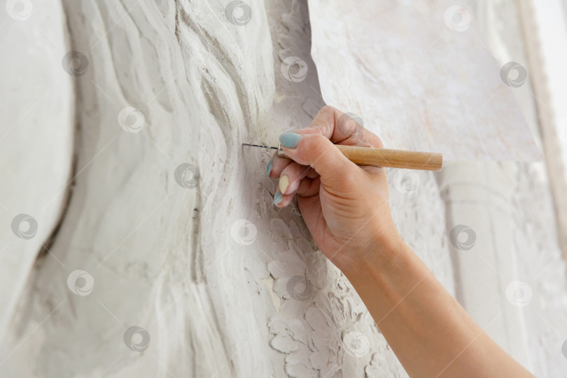 Скачать Рабочий процесс: женская рука резцом вырезает барельефный узор фотосток Ozero