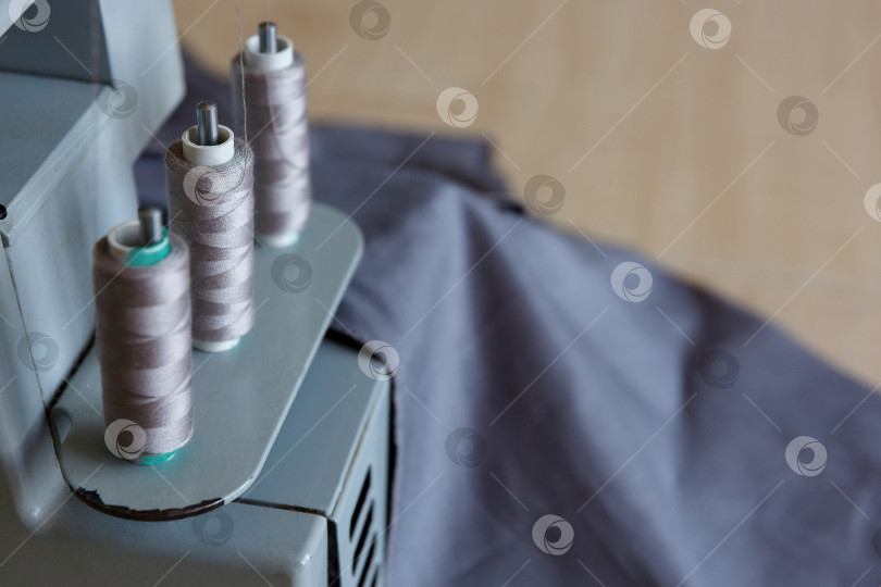 Скачать Натюрморт. Принадлежности для шитья. Нитки для оверлока и серая ткань фотосток Ozero