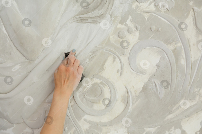 Скачать женщина за работой обрабатывает наждачной бумагой барельеф на стене фотосток Ozero