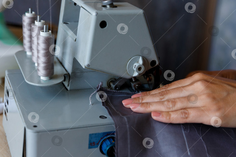 Скачать Рабочий процесс. Швея обрабатывает край ткани оверлоком фотосток Ozero
